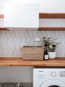 Washing machine under wooden table with plant and wicker basket